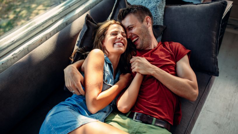 A couple laugh and hold each other.