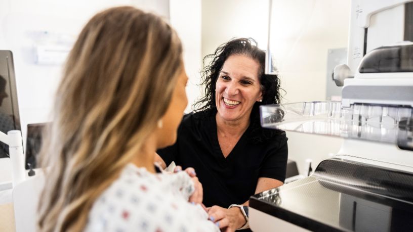 A woman talking to a friendly nurse ahead of a mammogram.