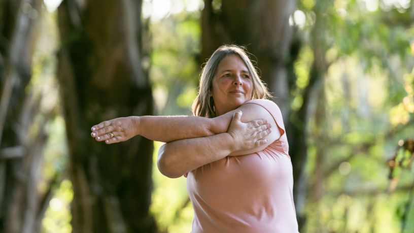 A woman stretching her arms outside.