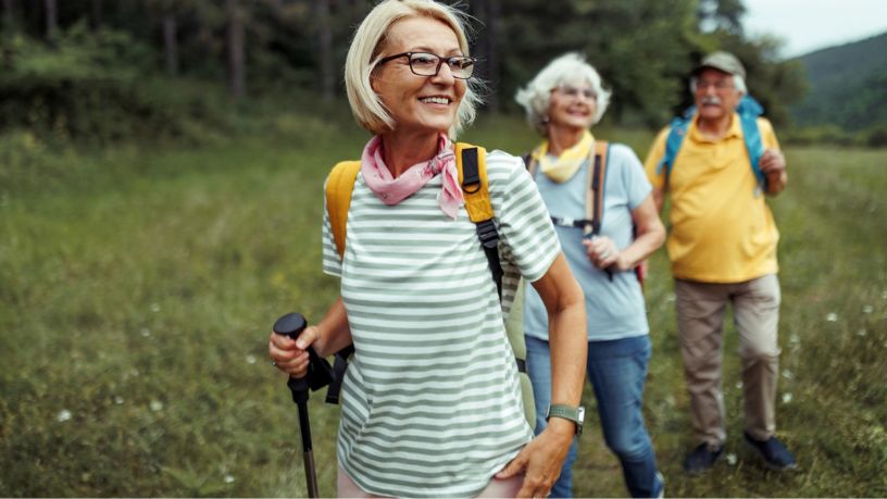 Woman hiking on a green trail with her older parents in a natural landscape.