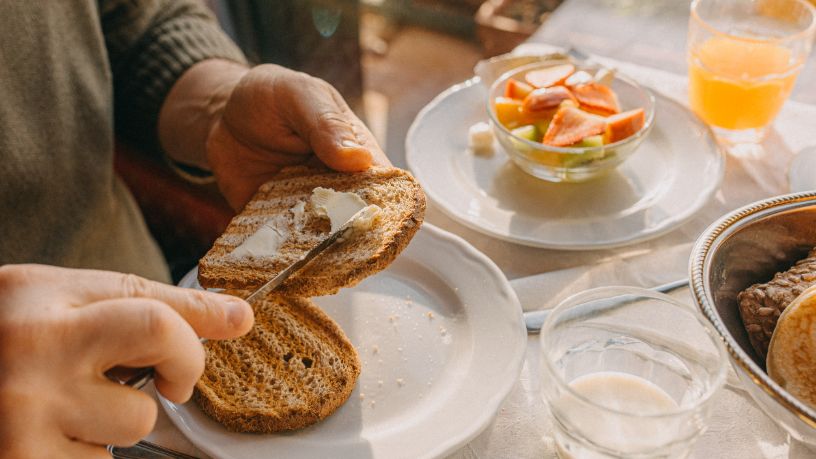 A person spreads butter on their toast.