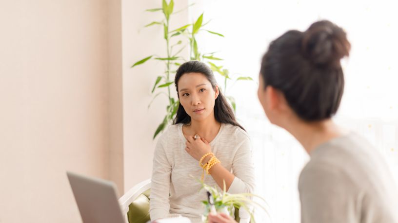 Two women speak in front of a laptop at a clinic.