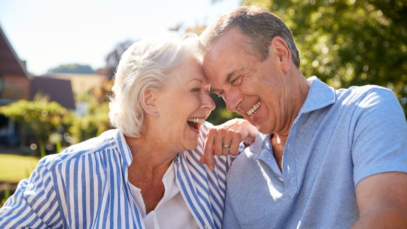 A man and woman laugh together outside.