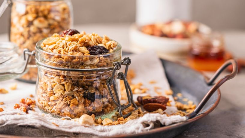 A jar filled with homemade muesli is rustically displayed on a serving tray.