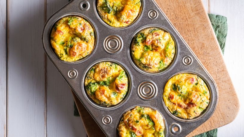 A tin is filled with freshly baked kale, egg and heirloom tomato breakfast muffins.