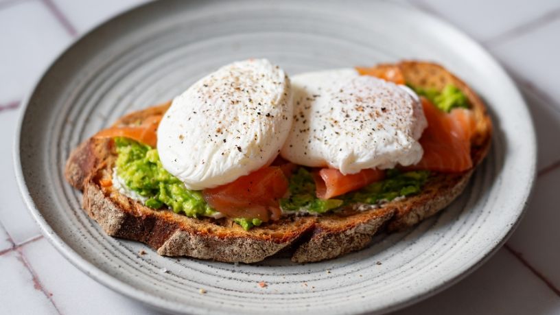 A plate is filled with poached eggs on toast with avocado and smoked salmon.