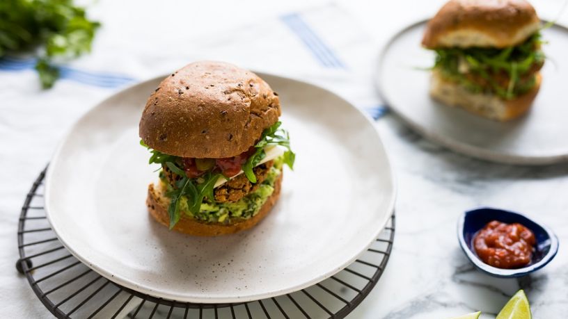 Two Mexican bean burgers sit on plates side by side.