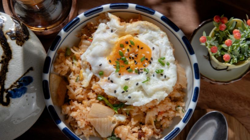 A bowl filled with slow cooked pork bibimbap on rice with a fried egg on top.