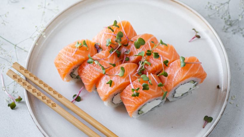 Several smoked salmon rolls are neatly arranged on a plate.
