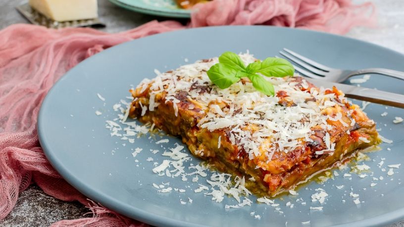 A plate of lasagne sits on a table.