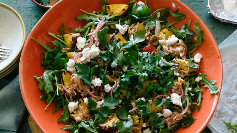 A salad bowl is filled with chargrilled peach salad.