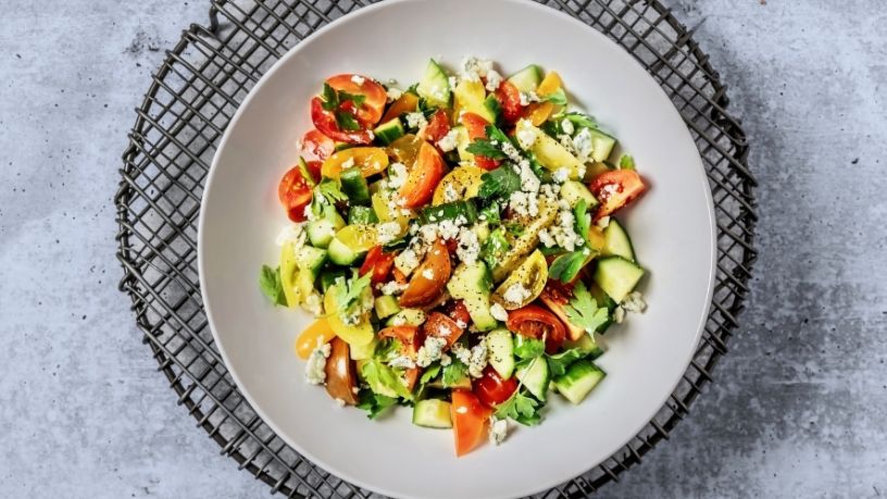 A bowl of chargrilled spring vegetable and tomato salad sits on a wire rack