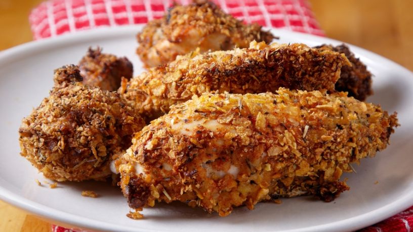 A plate of crispy chicken strips sits on a table.