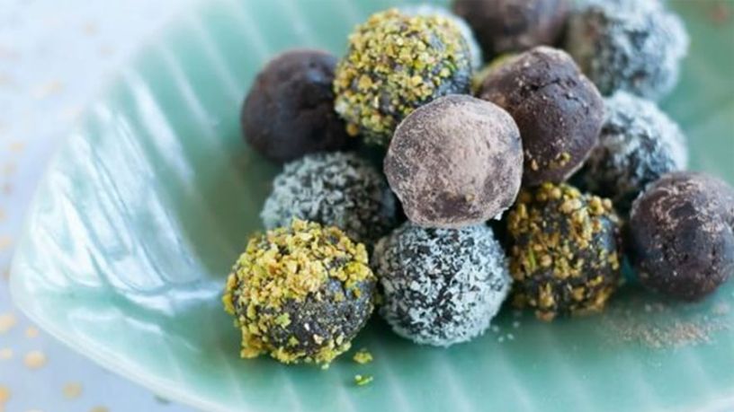 Several chocolate truffles are arranged onto a leaf-shaped serving dish.