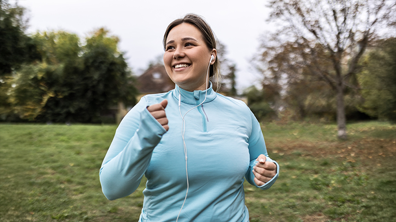 A woman in a blue top walking and smiling.