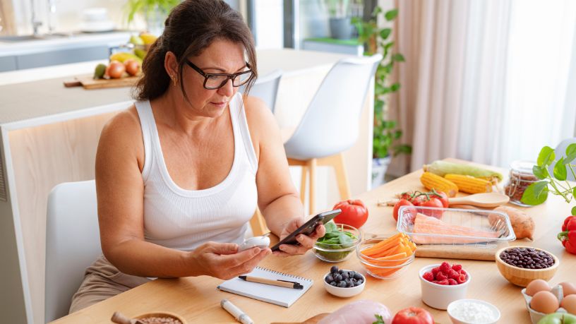 A woman looking at an iPad with bowls of healthy food in front of her. 