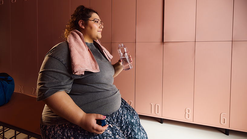 A woman drinking water at the gym after a workout. 