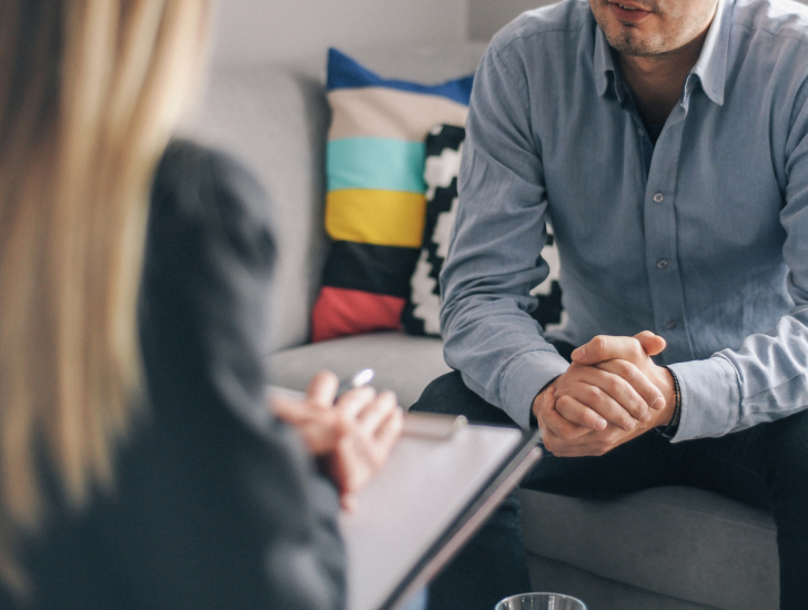 A therapist talking to a patient sitting on a couch